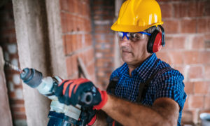 Senior construction worker with a drill.